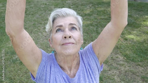 Senior citizen female enters frame during a yoga pose.