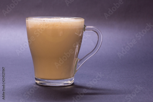 Transparent glass cup with coffee on violet background. Bright tone, soft focus