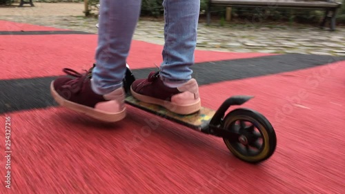 Close up of a child riding scooter, tracking shot photo