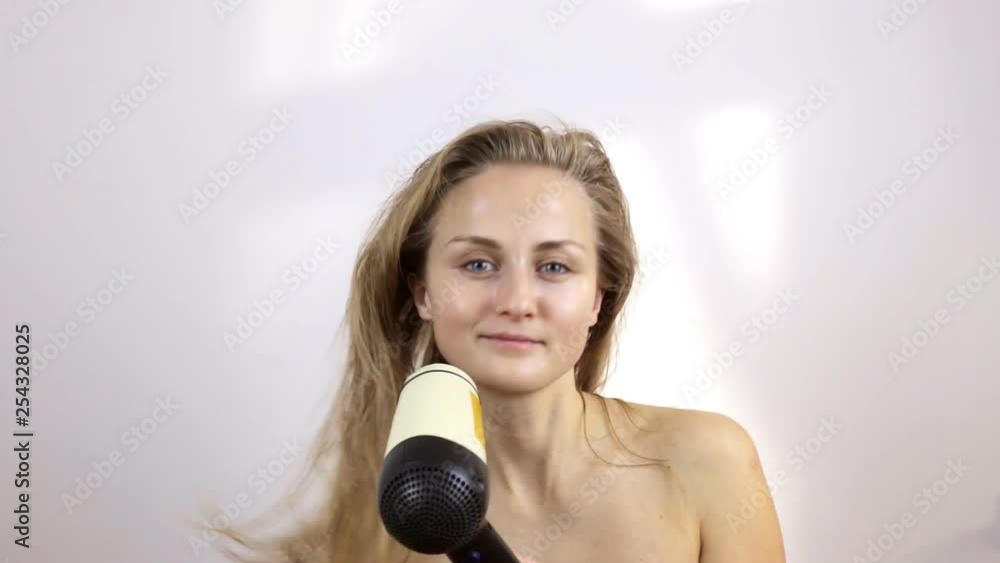 Young woman after taking a shower dries wet hair Young woman after taking a shower dries wet hair