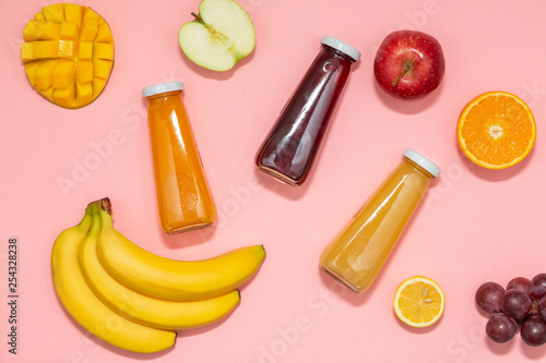 Colorful smoothies in bottles with fresh fruits on pink background. Flat lay, top view. Natural Organic Food Style.