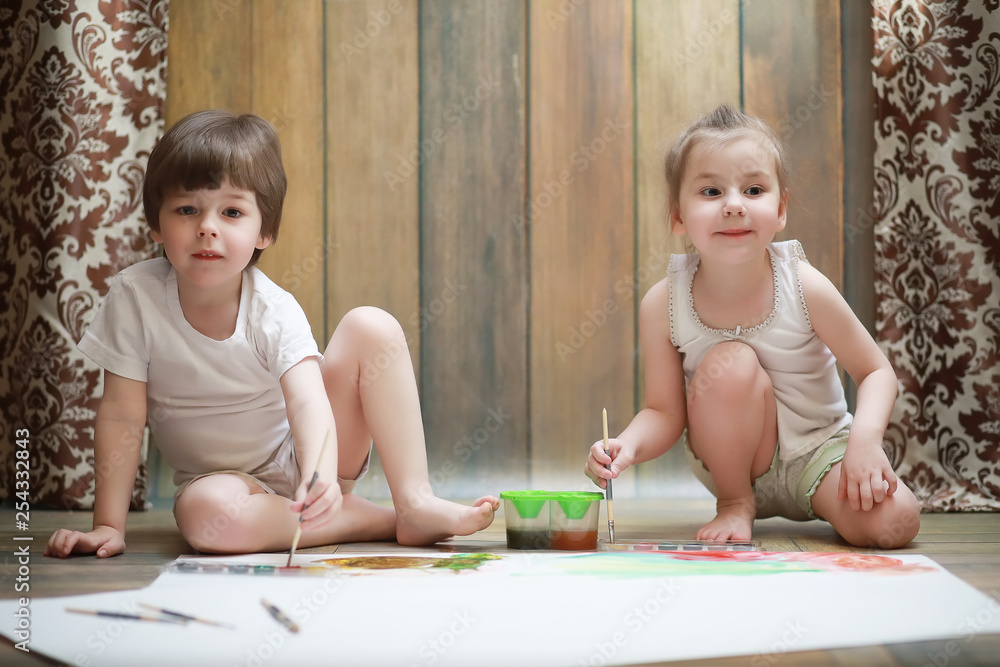 Little children paint on a large sheet of paper Little children paint on a large sheet of paper