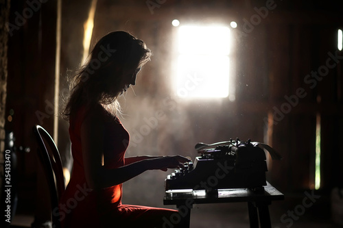 A girl in retro style prints on an old typewriter