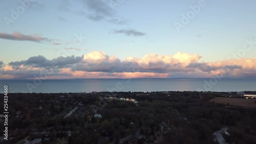 Rising drone footage before a landscape with a view of the water at sunset with huge puffy pink clouds. photo