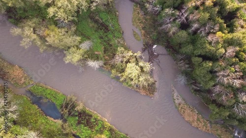 Top-down drone footage over a brown river surrounded by trees. photo