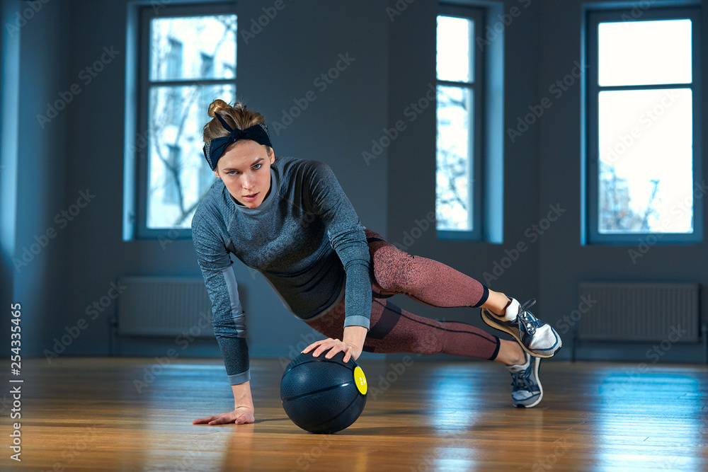 © Georgii - Fit and muscular woman doing intense core workout with kettlebell in gym. Female exercising at crossfit gym.