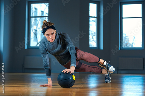 Fotografia Fit and muscular woman doing intense core workout with kettlebell in gym