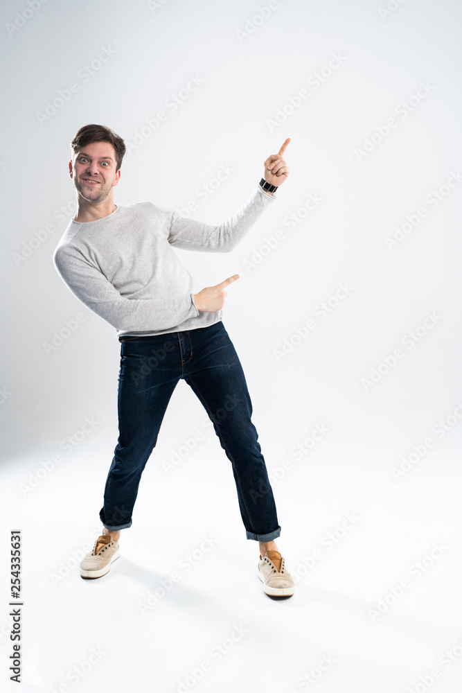 Full length portrait of a cheerful young man wearing casual clothes isolated over white background, pointing away at copy space. Full length portrait of a cheerful young man wearing casual clothes isolated over white background, pointing away at copy space.