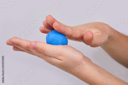 The process of play dough modeling, the child's hands sculpt figures. Play dough in preschool or nursery for education concept. Piece of blue plasticine in the hand. 
