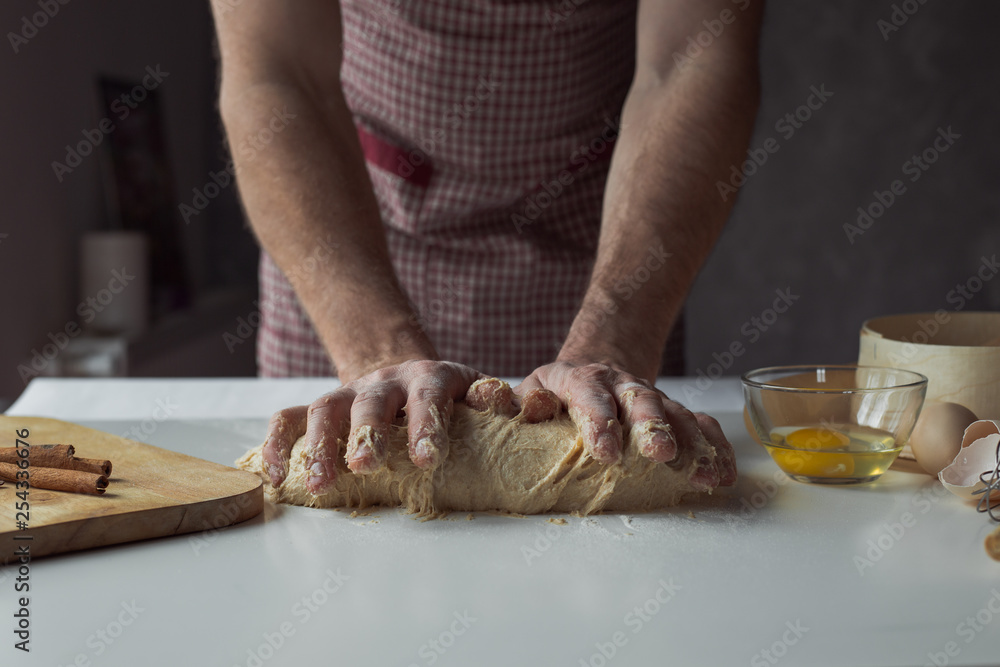 A handful of flour with egg on a rustic kitchen. Against the background of men's hands knead the dough A handful of flour with egg on a rustic kitchen. Against the background of men's hands knead the dough