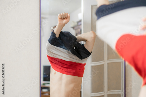 boy put on shirt at home standing in front of the mirror in the morning photo