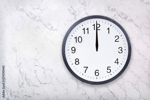 Wall clock show the twelve o'clock on white marble texture. Office clock show midday or midnight on marble background