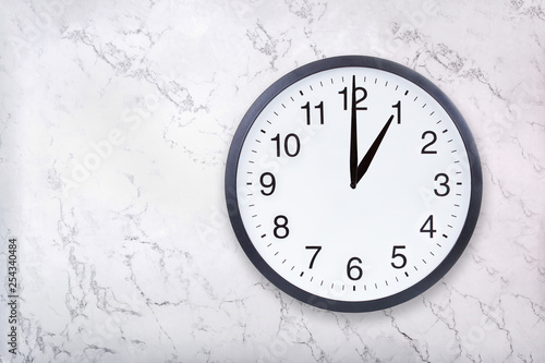 Wall clock show one o'clock on white marble texture. Office clock show 1pm or 1am on marble background