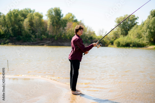 young boy fisherman fishing on a river bank