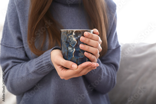 Young woman drinking hot tea at home, closeup