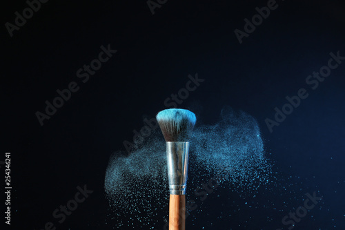 Fotografía Makeup brush and burst of eyeshadows on dark background