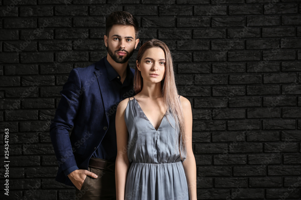 Fashionable young couple near dark brick wall