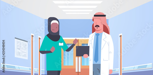 arab doctor and african arabic nurse medical team discussing in hospital corridor healthcare concept modern clinic interior portrait horizontal flat