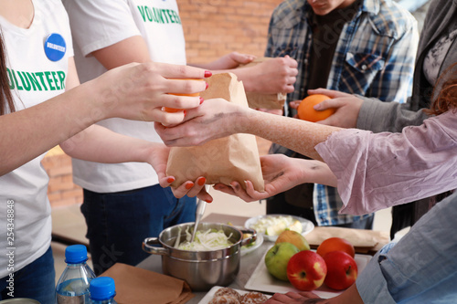 Young volunteers giving food to poor people