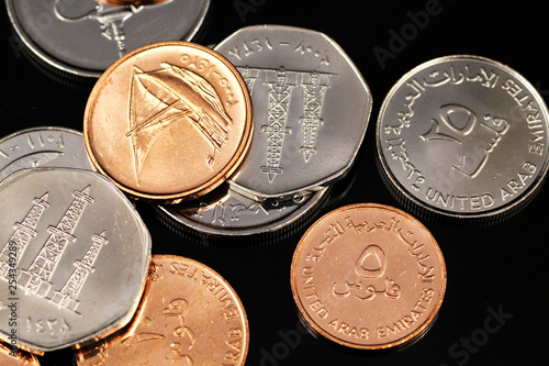 A macro image of assorted coins from the United Arab Emirates on a reflective black background photo