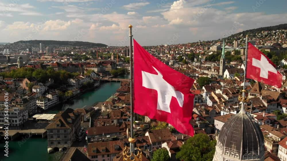 Aerial circling drone shot around Swiss flags on Grossmünster church in Zürich Switzerland closer