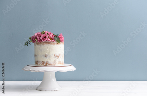 Stampa su tela Sweet cake with floral decor on table against color background