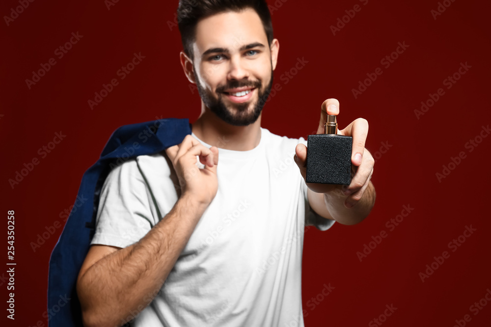 Handsome man with bottle of perfume on color background Handsome man with bottle of perfume on color background