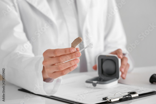 Female doctor with hearing aid and box at table  closeup