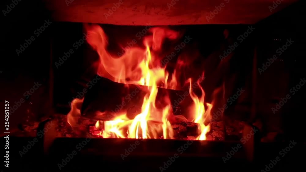 Slow-motion zoom-in to an iron fireplace burning vividly some logs with large flames. Approaching slowly the fireplace moving forward on a frontal view. Slow-motion zoom-in to an iron fireplace burning vividly some logs with large flames. Approaching slowly the fireplace moving forward on a frontal view.