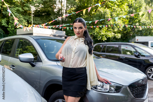 Attractive brunette offering key from new car
