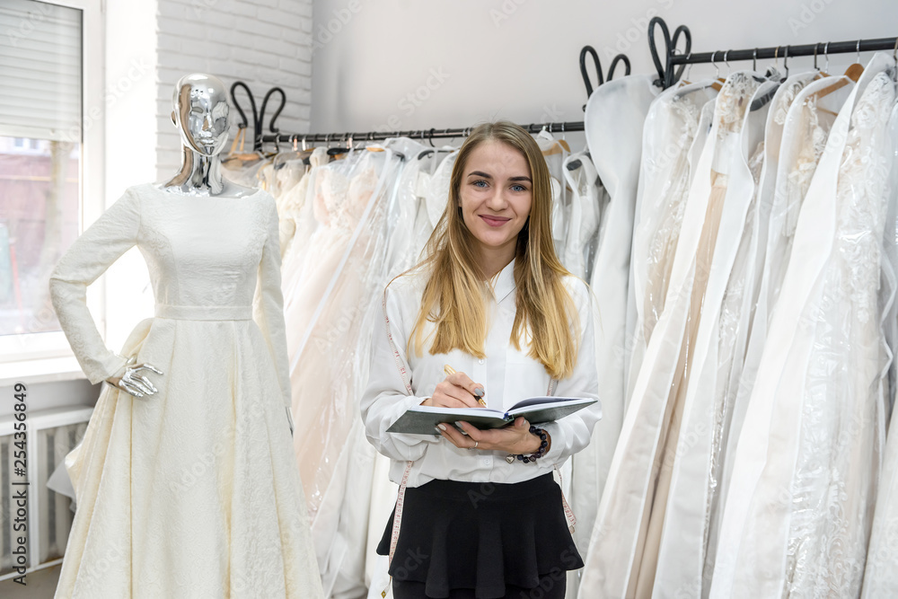 Young tailor with notepad in wedding salon Young tailor with notepad in wedding salon
