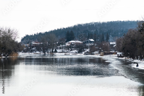 Houses in winter forest near river. Wooden houses on mountain