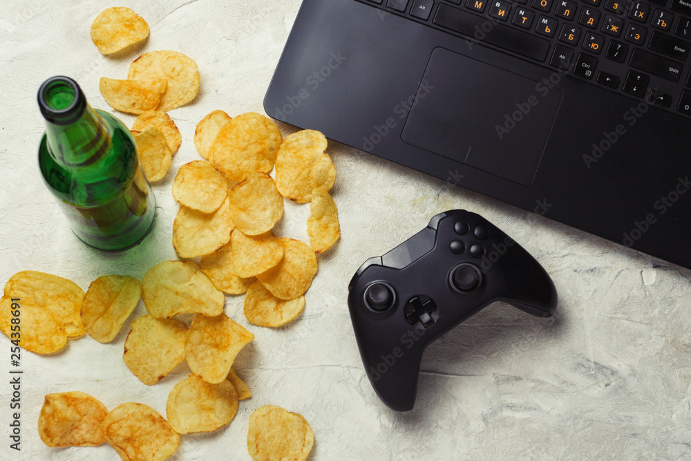 Laptop, Gamepad, Potato chips, Bottle of Beer on a light stone background.  Concept of computer games and leisure Stock Photo | Adobe Stock