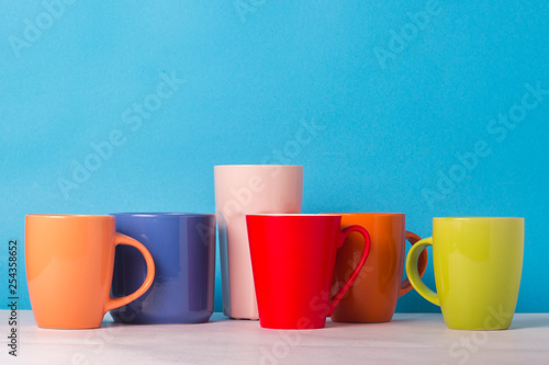 Many multicolored cups of coffee or tea on a blue background. The concept of a friendly company, a large family, meeting friends for a cup of tea or coffee photo