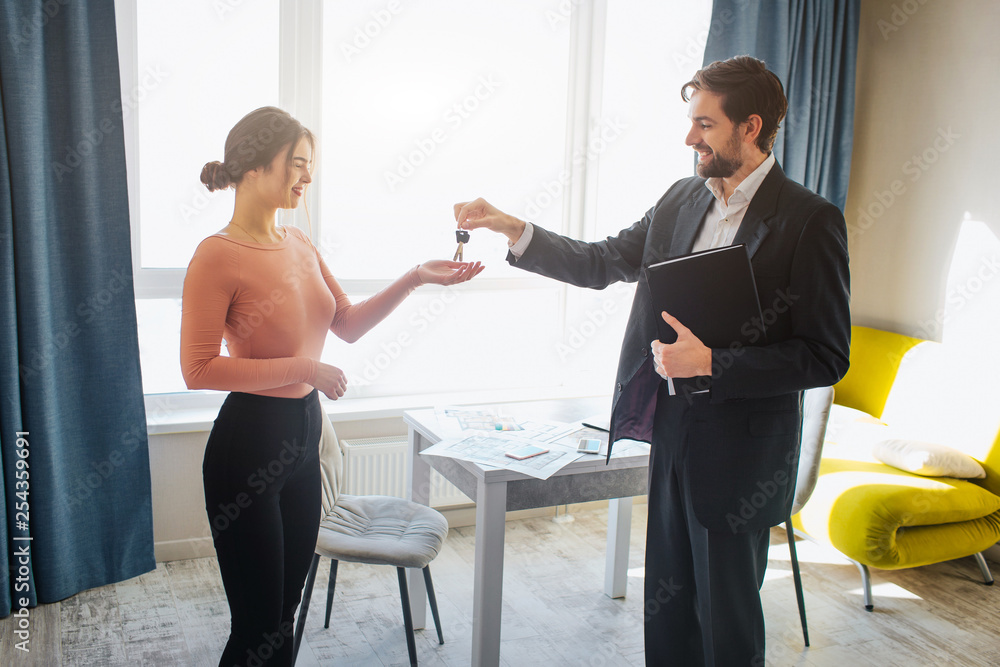 Obraz premium Young woman buy rent apartment. She get keys from realtor. Happy and joyful. Business deal in office room. Bright daylight.