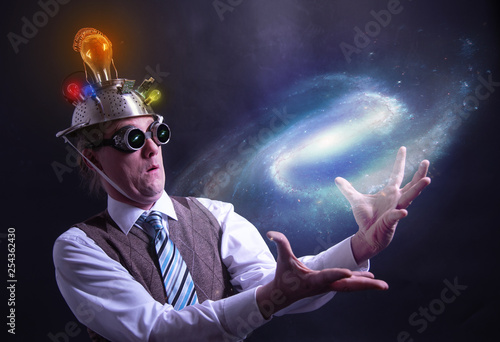 distraught looking conspiracy believer in suit with aluminum foil head holding the galaxy or universe in his hands