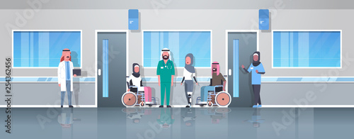 arabic doctors taking care of disabled injured people arab patients sitting in wheelchair woman with prosthetic leg disability concept hospital corridor clinic interior full length