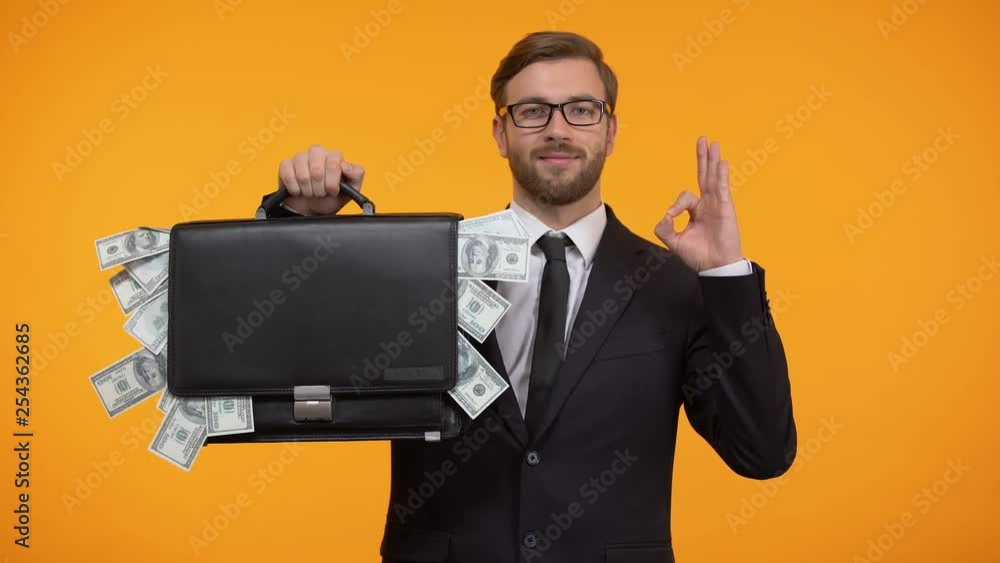 Male showing briefcase with money and doing ok gesture, payday lending service Male showing briefcase with money and doing ok gesture, payday lending service