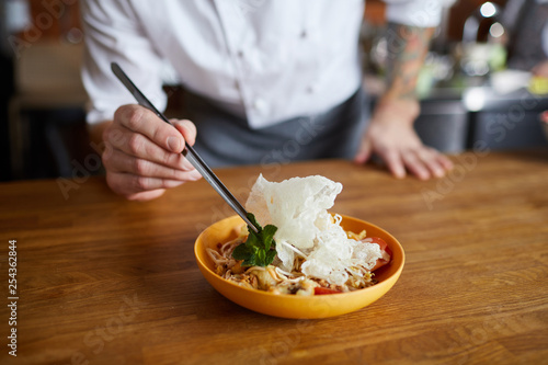 Obraz na plátně Close up of professional chef plating Asian cuisine dish in restaurant, copy spa