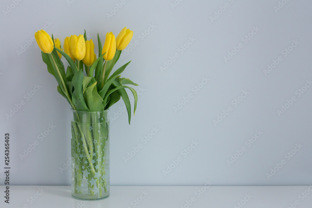 Yellow tulips in the vase on a white table