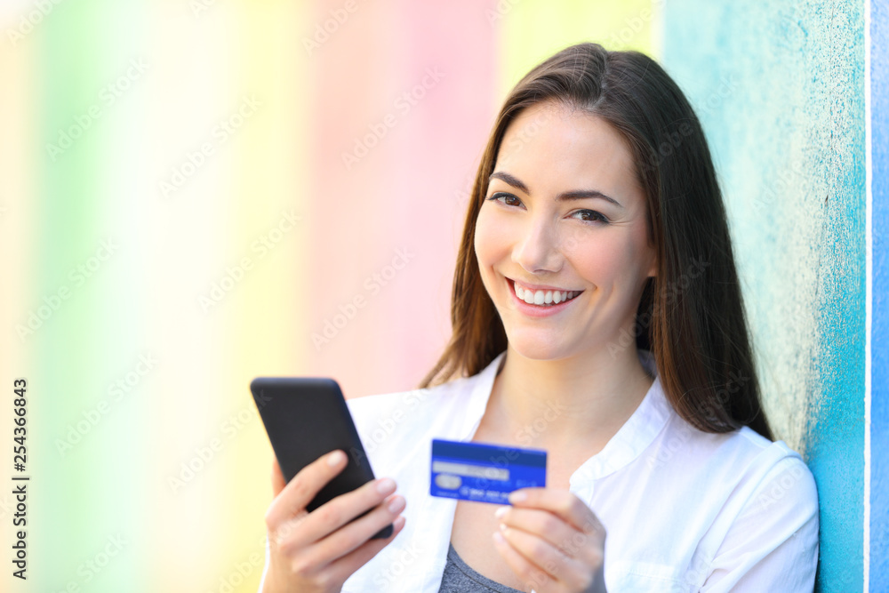 Fototapeta premium Online shopper holding phone and card looks at you