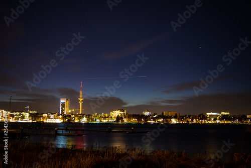A airplane s lights approaching Hamburg airport form a streak above downtown Hamburg at night