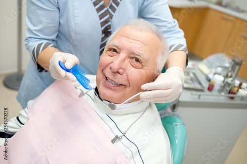 Closeup portrait of senior man in dental office sitting in dentist chair. Dental care for older people. Dentistry, medicine and health care concept