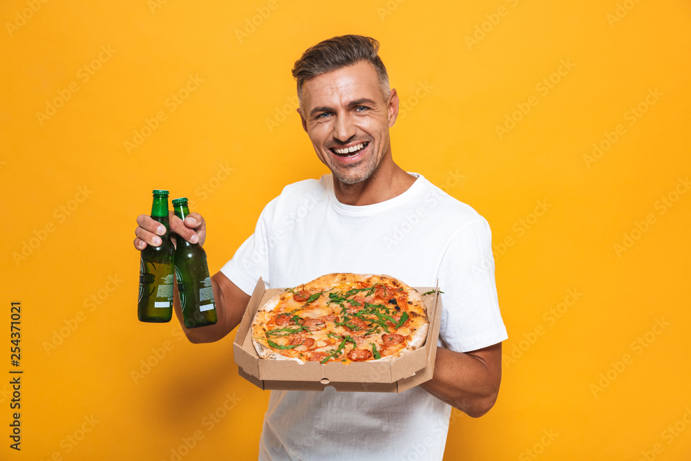 Image of adult man 30s in white t-shirt drinking beer and eating pizza while standing isolated Image of adult man 30s in white t-shirt drinking beer and eating pizza while standing isolated