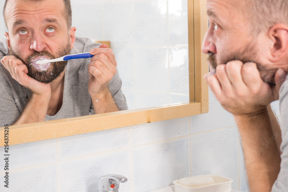 Bored guy brushing his teeth in bathroom