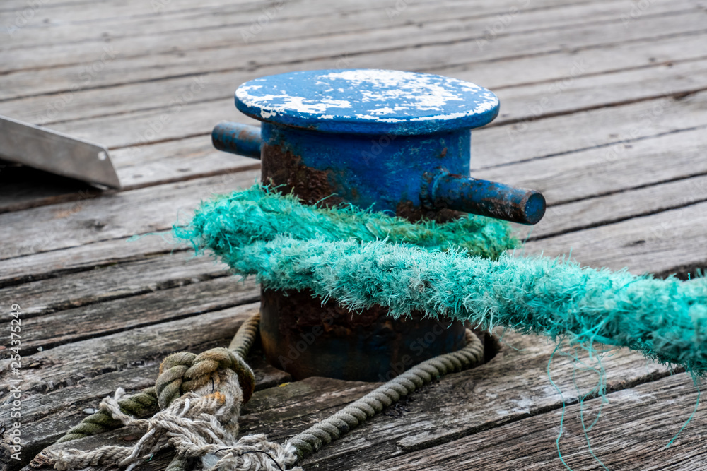 Poller mit dickem Tau, an dem ein Schiff festgemacht wird.