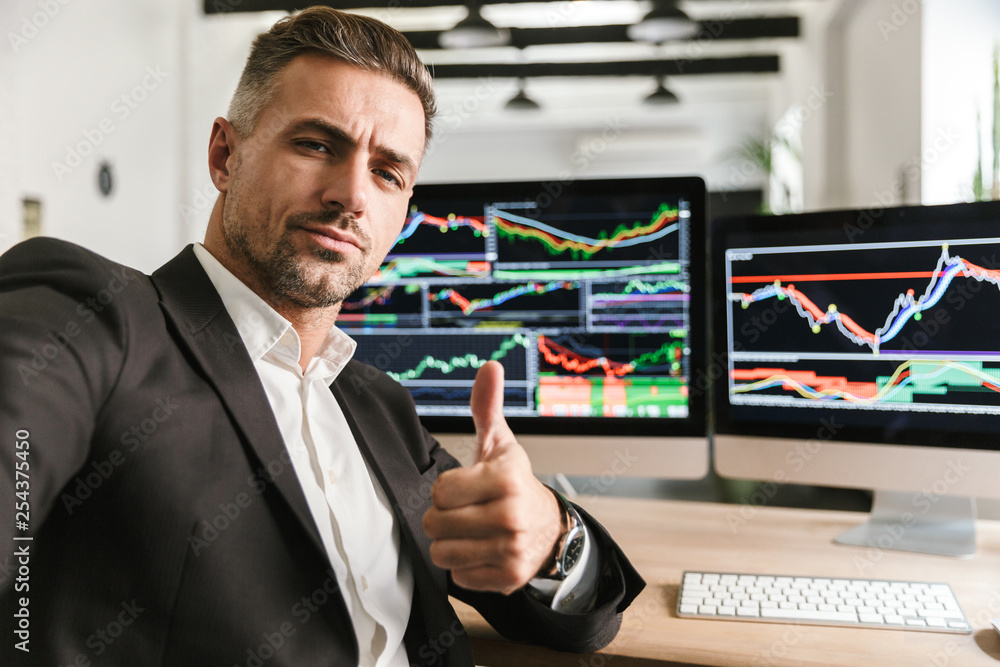 Photo of businesslike man taking selfie while working in office on computer with graphics and charts Photo of businesslike man taking selfie while working in office on computer with graphics and charts