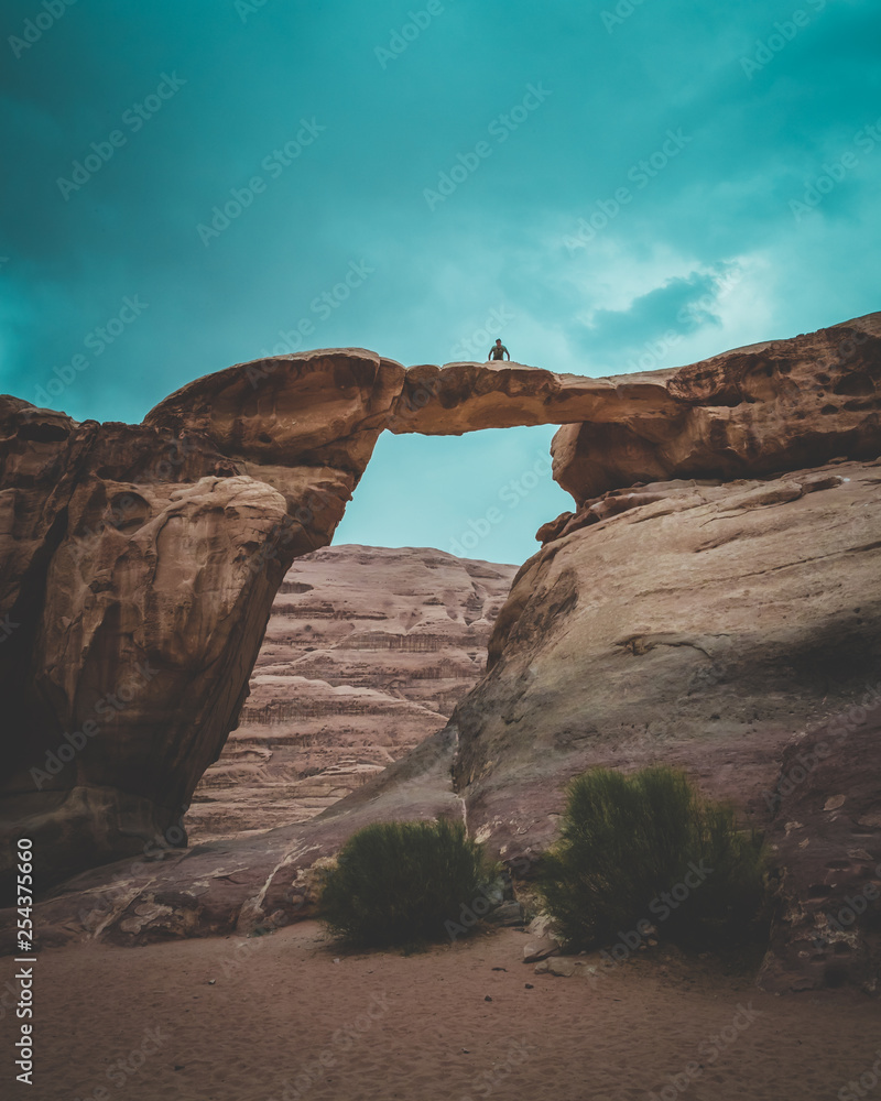 Photo d'un homme sur un pont naturel dans le désert, Jordanie, Wadi Rum