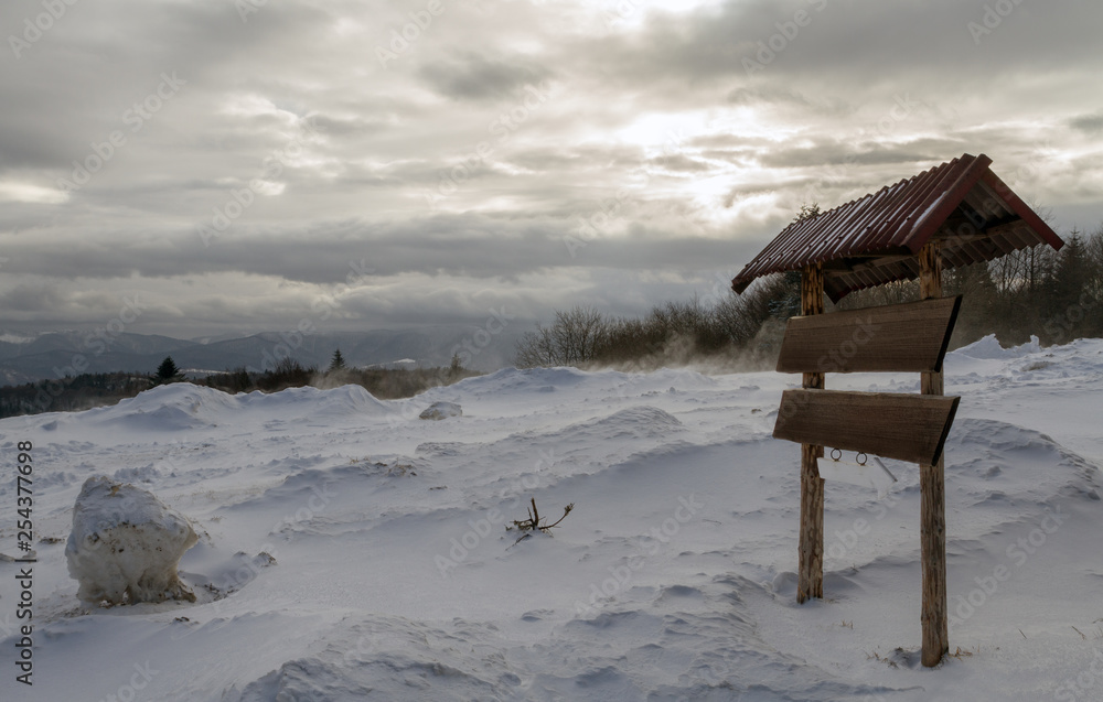 Fototapeta premium Wooden sign on snowy and windy mountain