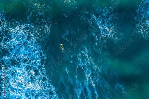 Looking down at surfer in the ocean - aerial view